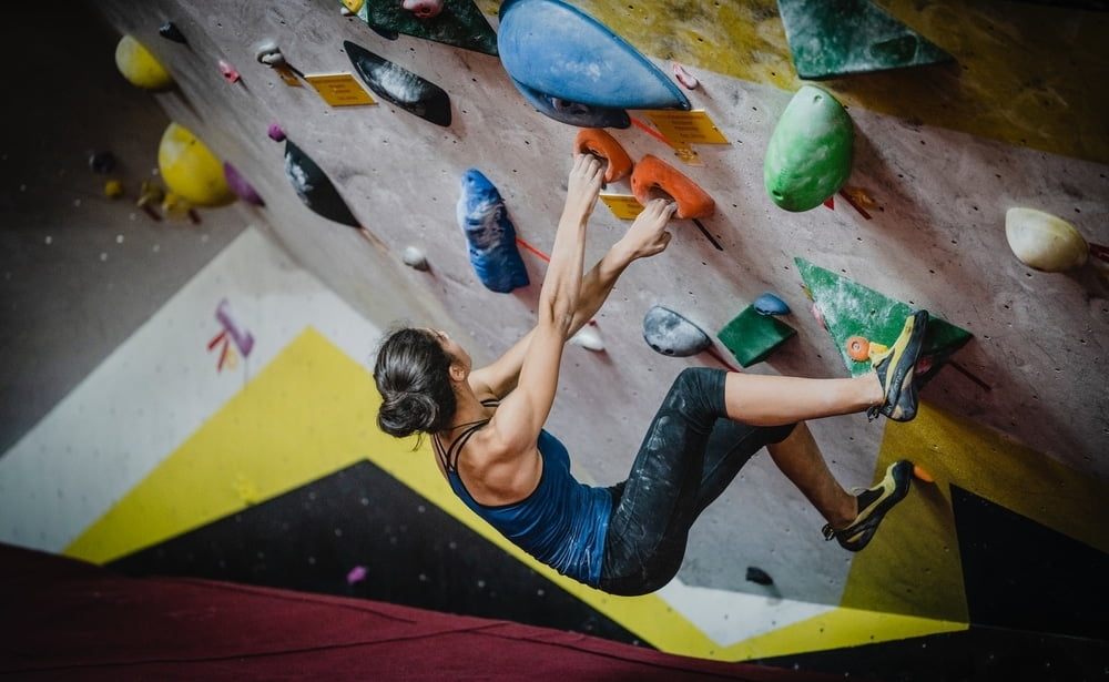 A woman breaking in her climbing shoes at a climbing gym