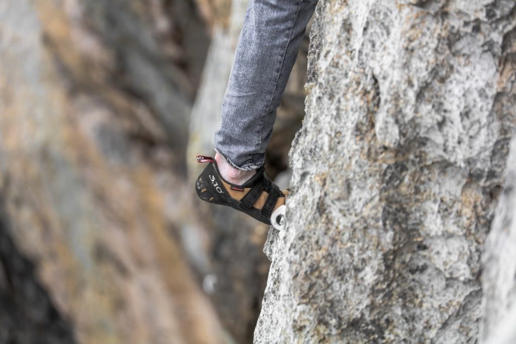 Person wearing grey jeans rock climbing