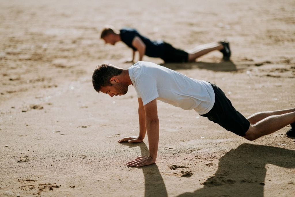 Two men exercise on beach