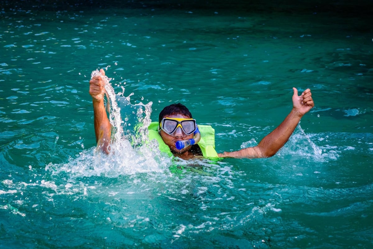 Scuba diver on water surface holding up arms